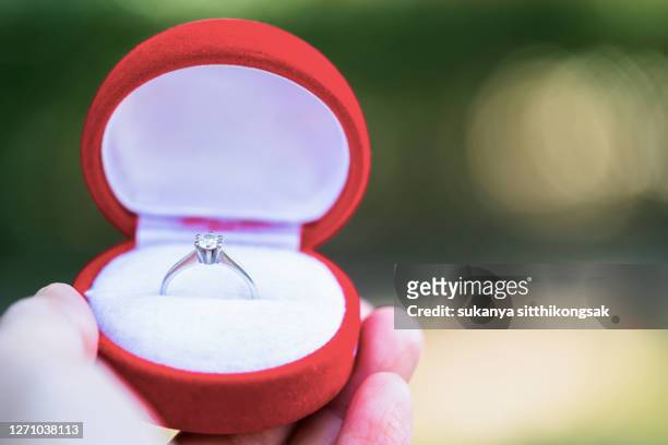 close up of man hand holding open red box with engagement ring silver diamond. - man holding ring box stock pictures, royalty-free photos & images