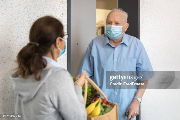 quarantine – woman helping senior man - assisted living community stock pictures, royalty-free photos & images