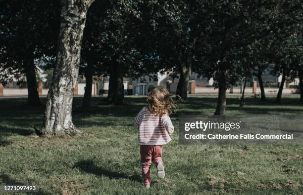 girl running away on grassy area - cara oculta fotografías e imágenes de stock