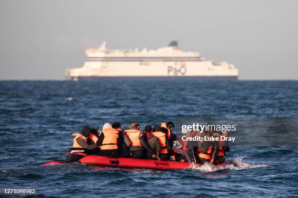 Migrants packed tightly onto a small inflatable boat bail water out as they attempt to cross the English Channel near the Dover Strait, the world's...
