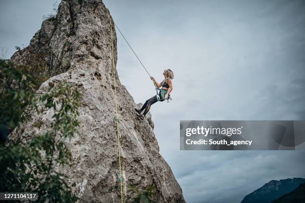 eine athletische klettererin klettert vom berg - woman climbing rope stock-fotos und bilder