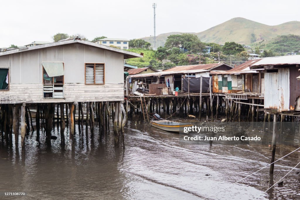 Wooden houses over the water in floating village with children sitting in the porch