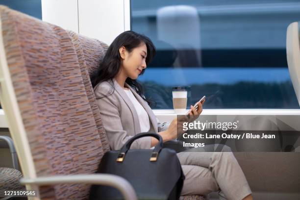 young businesswoman using smartphone on high-speed train - railroad car ストックフォトと画像