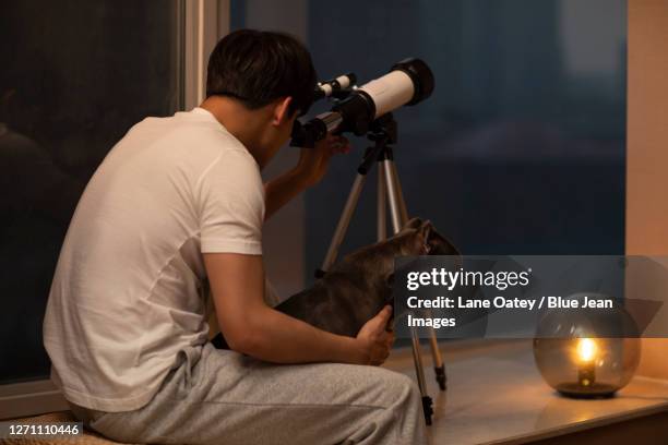 young man using telescope at home - one animal stock pictures, royalty-free photos & images