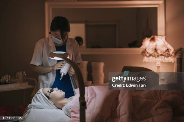 asian chinese laser pulses clean skin of the face. hardware cosmetology treatment. process of photosynthesis, warming the skin, laser carbon facial skin rejuvenation - laser stock pictures, royalty-free photos & images
