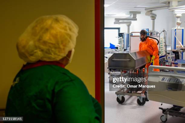 Health worker wears a protective suit and gloves as he transfers the body of a deceased COVID-19 patient to a metal coffin at the ICU of Krakow...