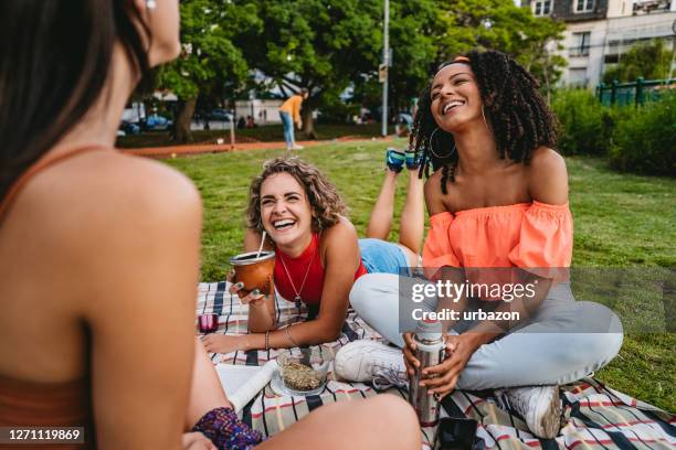 three young women on picnic in public park - park picnic stock pictures, royalty-free photos & images