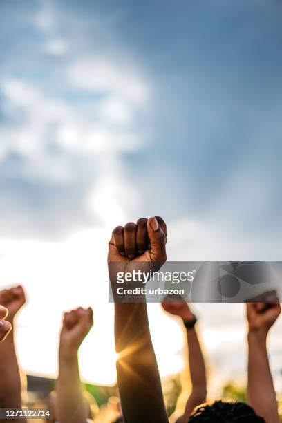 protestors raising fists - sindicato imagens e fotografias de stock