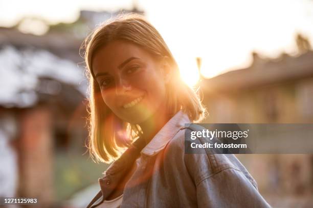 lens flare shot of woman smiling at camera - portrait lens flare stock pictures, royalty-free photos & images