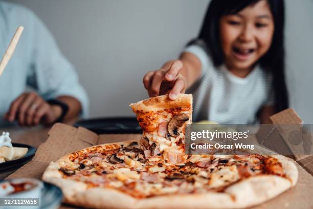 cheerful young girl holding a slice of pizza - pizza slice stock pictures, royalty-free photos & images