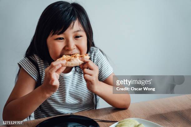 cheerful asian girl eating pizza - child foodie photos et images de collection