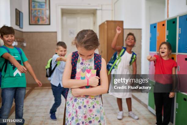 group of elementary school children mocking and laughing at a female student in a hallway - seven point stock pictures, royalty-free photos & images