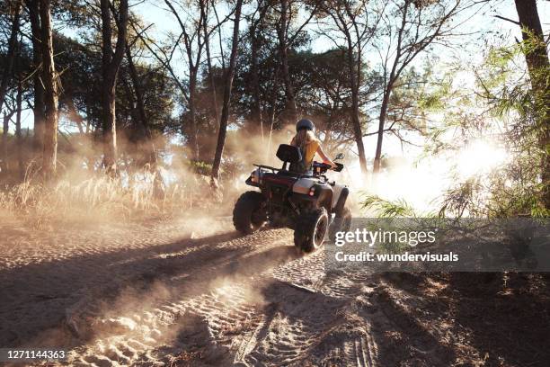 mujer rubia usando casco montando quad colina en el bosque - vehículo de todo terreno fotografías e imágenes de stock