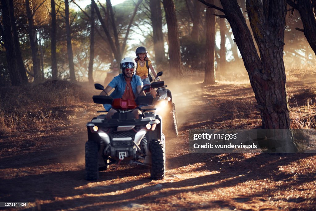 Zwei Freunde tragen Helme mit Spaß und fahren Quad-Bikes zusammen im Wald