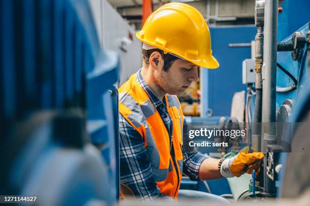 portrait of young manuel worker man working with ball valves in factory - district heating stock pictures, royalty-free photos & images