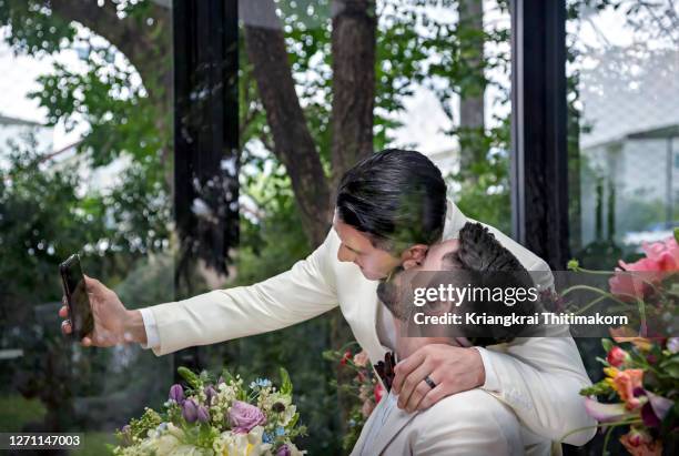 same sex couple doing selfie at the wedding day. - asian lesbians kiss stock pictures, royalty-free photos & images