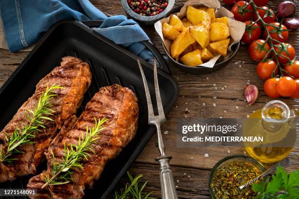 strip steak two steaks on cast iron cooking pan cooked - angus beef striploin stock pictures, royalty-free photos & images