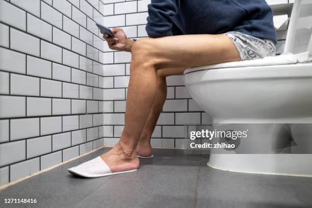 the man sitting on the toilet playing with his mobile phone - portable toilet - fotografias e filmes do acervo