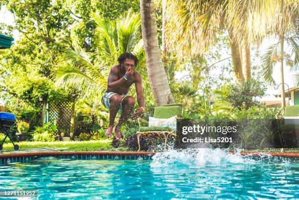 afroamerikanischer mann spritzt in hinterhof-pool - arschbombe stock-fotos und bilder