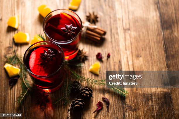 wine-filled glasses surrounded by pine needles, spices and orange slices - setting the bar stock pictures, royalty-free photos & images