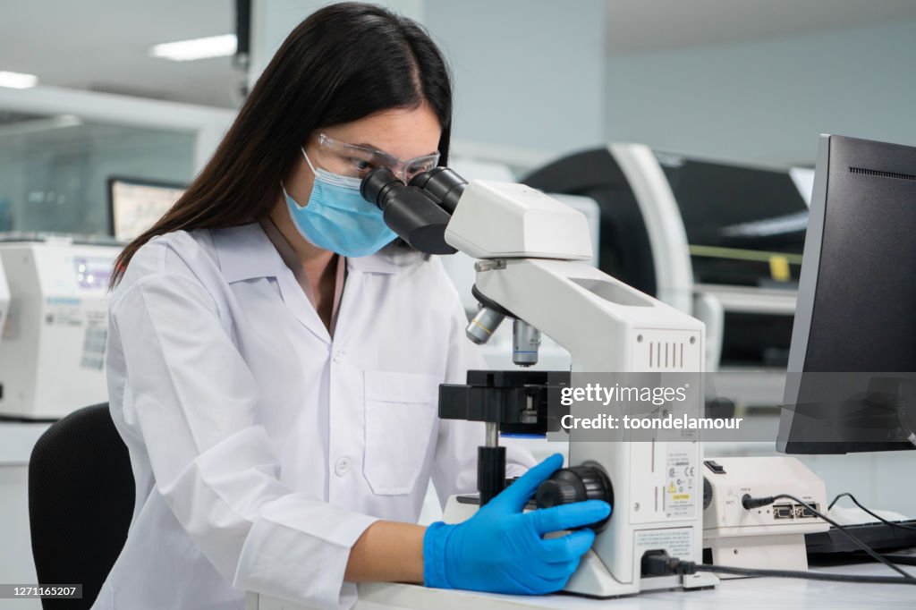 Women Scientist Looking at platelets experimental blood sample With a microscope.