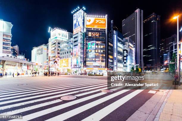 buildings illuminated with neon lights in shinjuku at night, tokyo, japan - empty street stockfoto's en -beelden