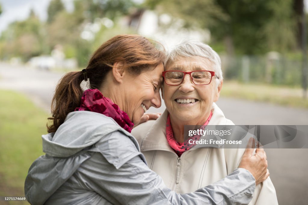 Mujer mayor feliz y cuidador caminando al aire libre