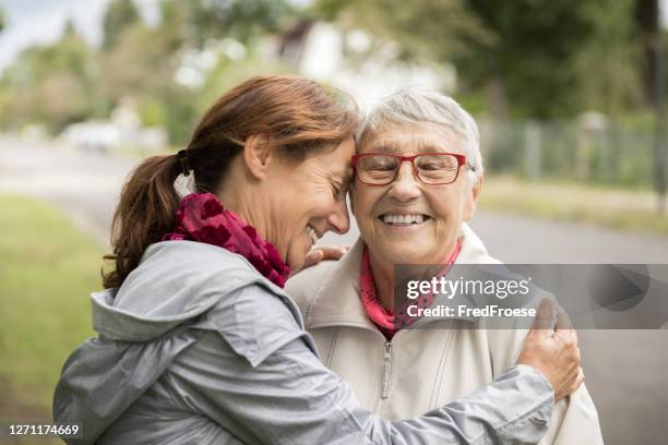 mujer mayor feliz y cuidador caminando al aire libre - ayudar fotografías e imágenes de stock