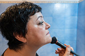 Middle-aged woman using makeup powder and brush