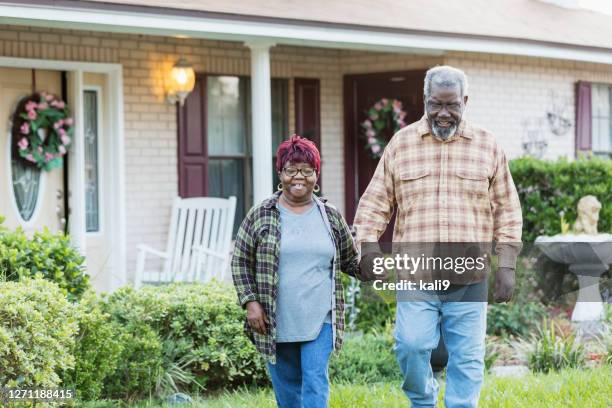 senior african-american couple walking in front of home - buildings side by side stock pictures, royalty-free photos & images