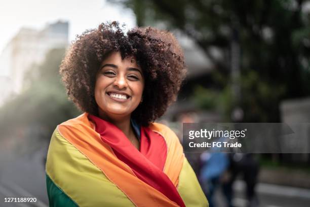 porträt einer glücklichen frau mit regenbogenflagge - gay flag stock-fotos und bilder