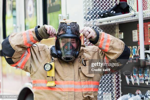 firefighter in fire protection suit and respirator mask - firefighter getting dressed stock pictures, royalty-free photos & images