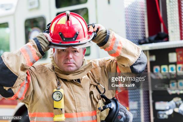 firefighter in fire protection suit putting on helmet - firefighter getting dressed stock pictures, royalty-free photos & images