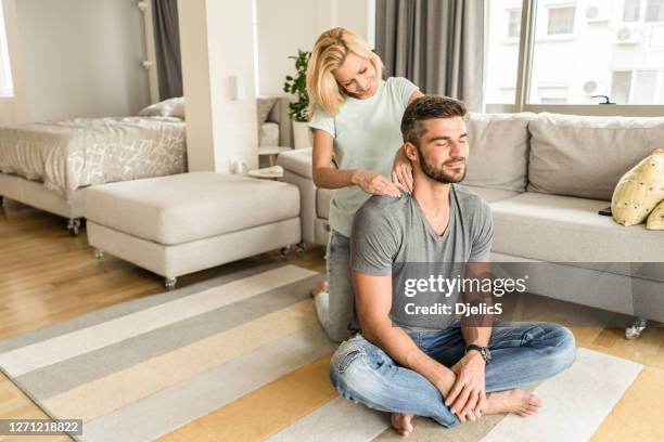 mid adult man receiving a relaxing shoulder massage from wife. - girlfriend massage stock pictures, royalty-free photos & images