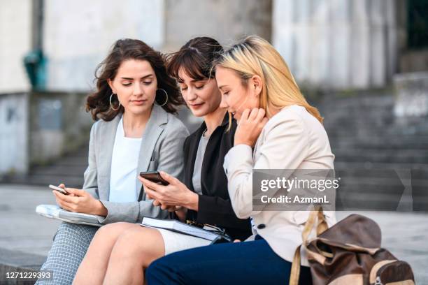 female law students sitting and checking smart phone - law school stock pictures, royalty-free photos & images