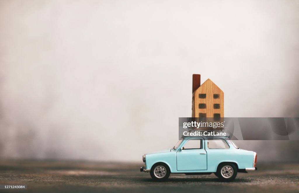 Pequeño coche azul con casa en el portaequipajes. Concepto de reubicación