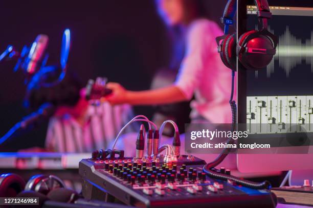 close up instruments ,musician is background. headphones hang on microphone with sound mixer board in home recording studio. - mixer foto e immagini stock