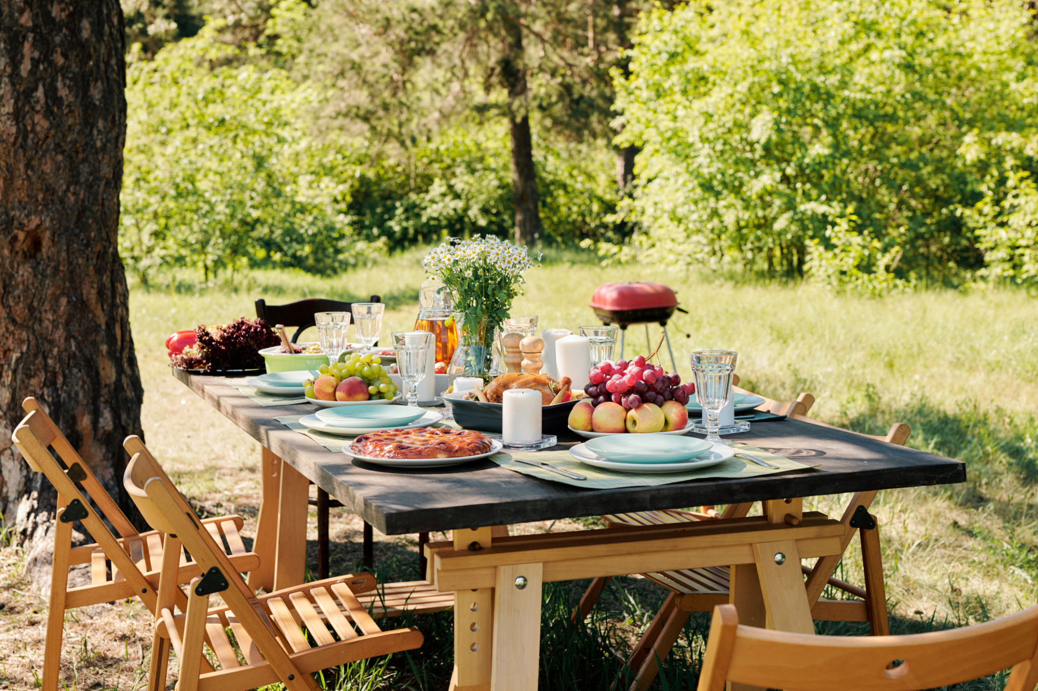 Group of chairs surrounding wooden served festive table with homemade food Group of chairs surrounding wooden served festive table with homemade food