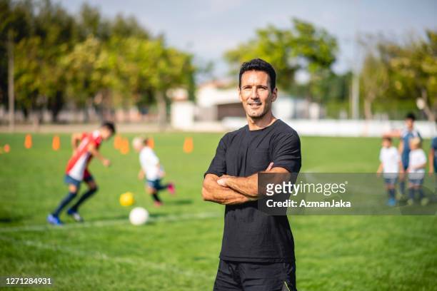portrait of male footballer coaching mixed age players - coach stock pictures, royalty-free photos & images