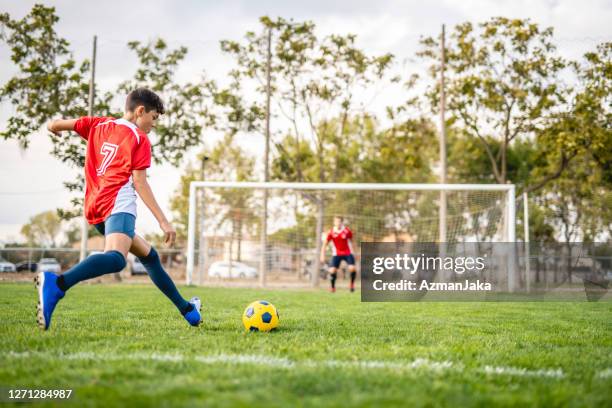 athletic boy footballer practicing kick to goal - soccer net stock pictures, royalty-free photos & images