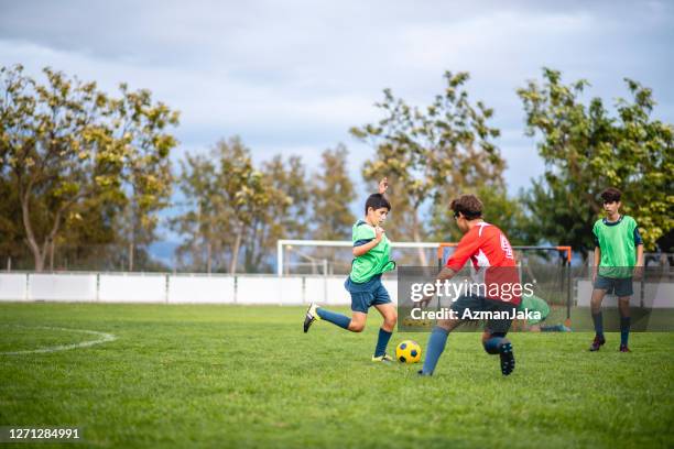 jogadores de futebol masculinos adolescentes driblando e defendendo na prática - youth sports competition - fotografias e filmes do acervo