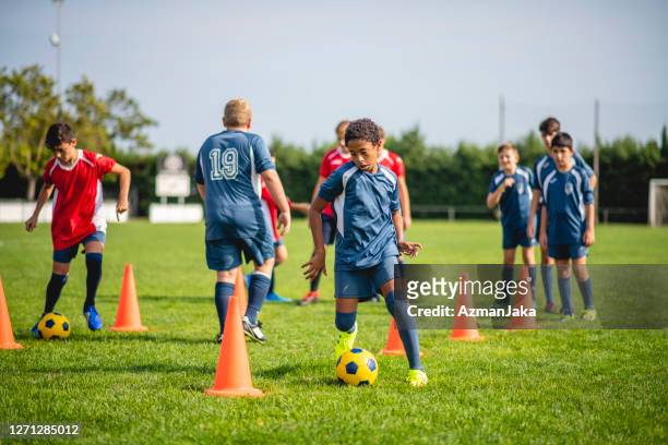 teenage male footballers doing dribbling drills on field - sports training camp stock pictures, royalty-free photos & images