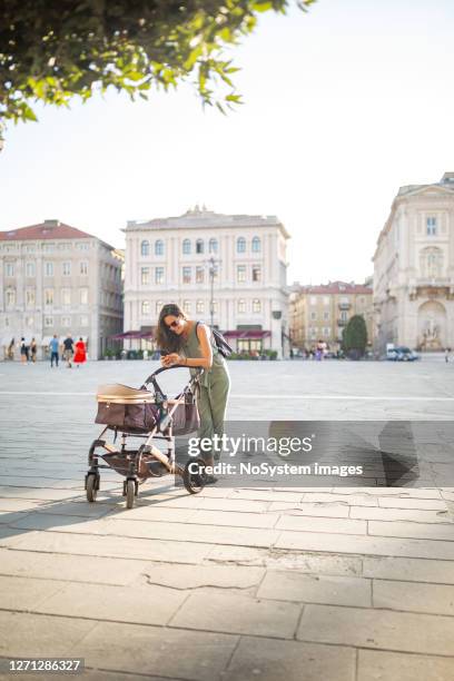 jeune femme italienne marchant avec son bébé - femme poussette rue photos et images de collection