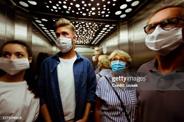 people wearing face mask in elevator - social distancing elevator stock pictures, royalty-free photos & images