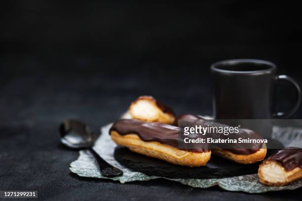traditional french eclairs with chocolate on dark background - powder puff stock pictures, royalty-free photos & images