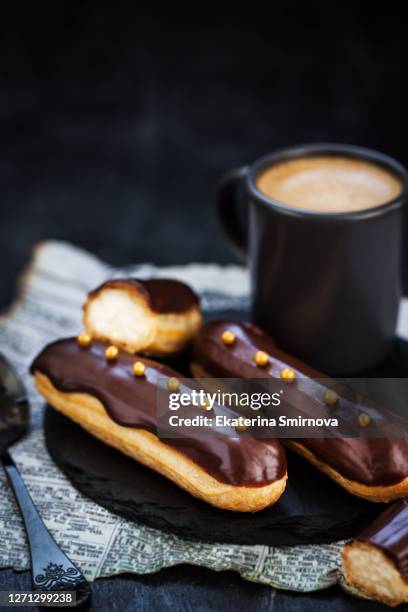 traditional french eclairs with chocolate on dark background - eclair stockfoto's en -beelden