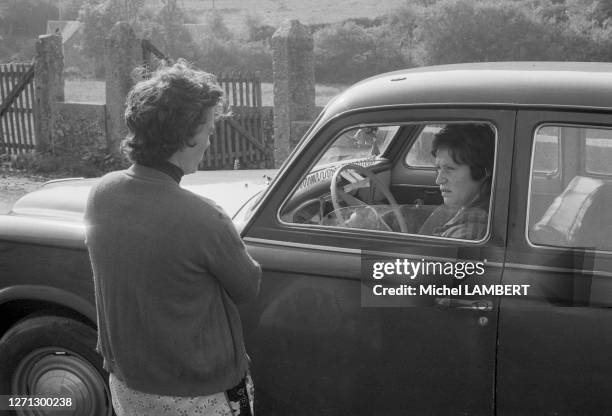 Agricultrice discutant avec une jeune femme en voiture en Normandie, en octobre 1975.