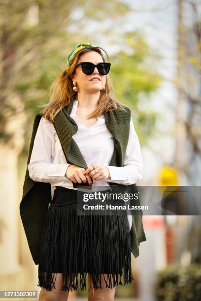 Designer Vanessa Moe wearing VanessaMoe head scarf and black fringe skirt, Gentle Monster sunglasses, khaki jumper, white shirt and red Hermes mules...