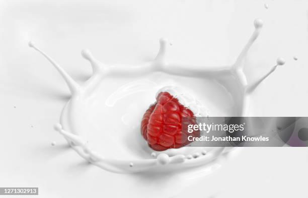 raspberry splashing in yogurt - splash crown fotografías e imágenes de stock