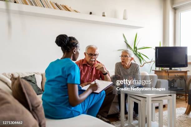 nurse in the home visit helping senior couple - home visit stock pictures, royalty-free photos & images